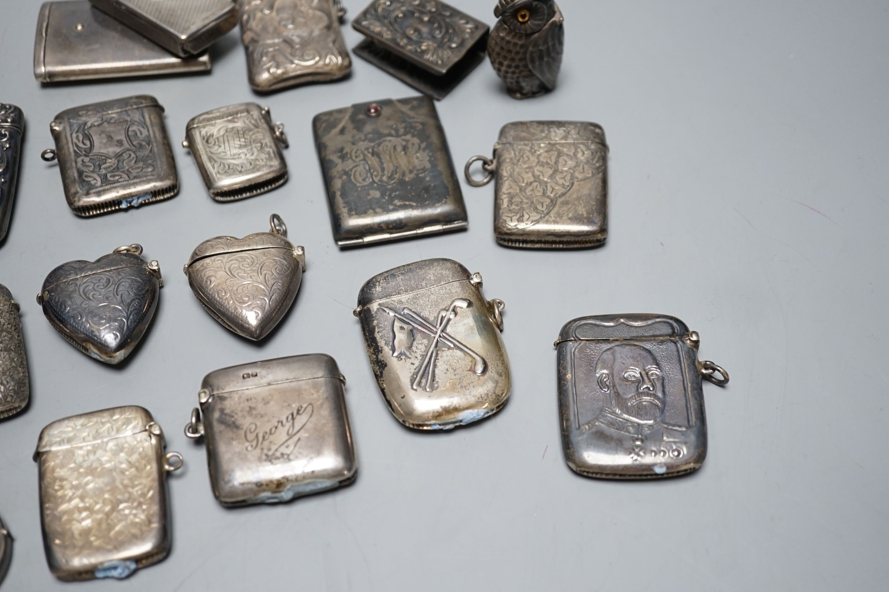 A collection of twenty six assorted mainly early 20th century silver or white metal vesta cases, including heart shape and combination vesta and cheroot cutter, largest 61mm and and seven assorted match cases or sleeves.